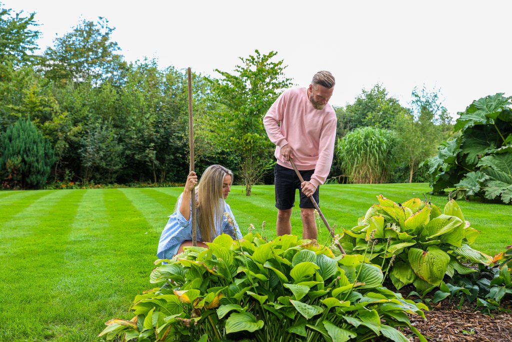 Et par er i gang med at vedligeholde græsplænen i haven